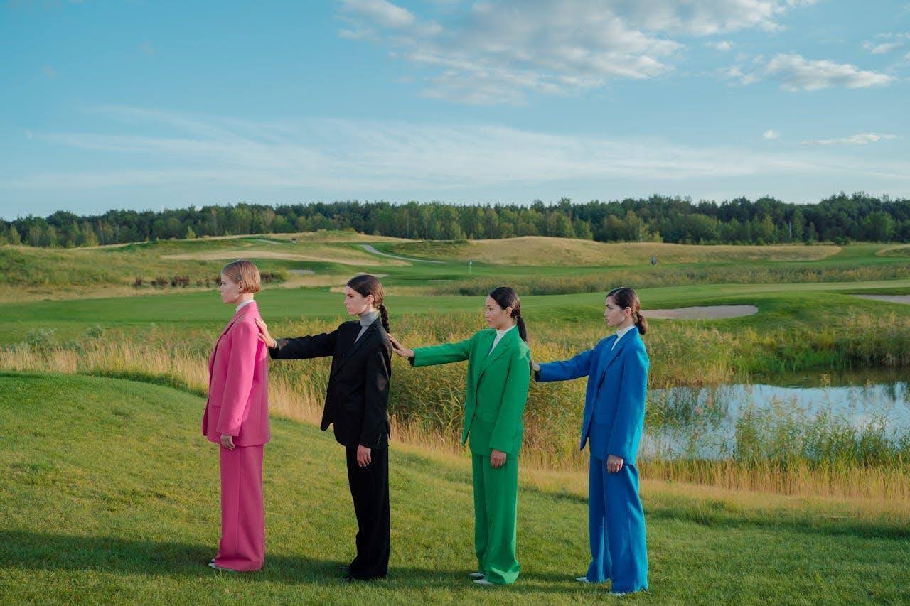 Four women wearing bold-colored oversized suits standing in a row, representing the revival of 80s fashion silhouettes